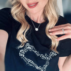 Woman wearing a black t-shirt with a white graphic design, holding her hand near her face.